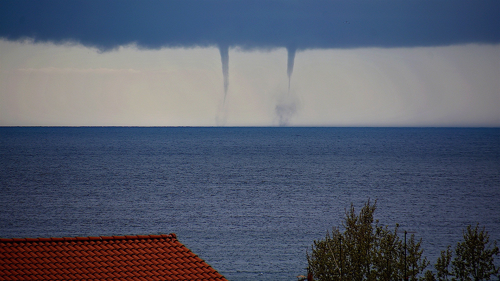  A wide, ominous, dark storm cloud and two waterspouts off the coast of Marseille